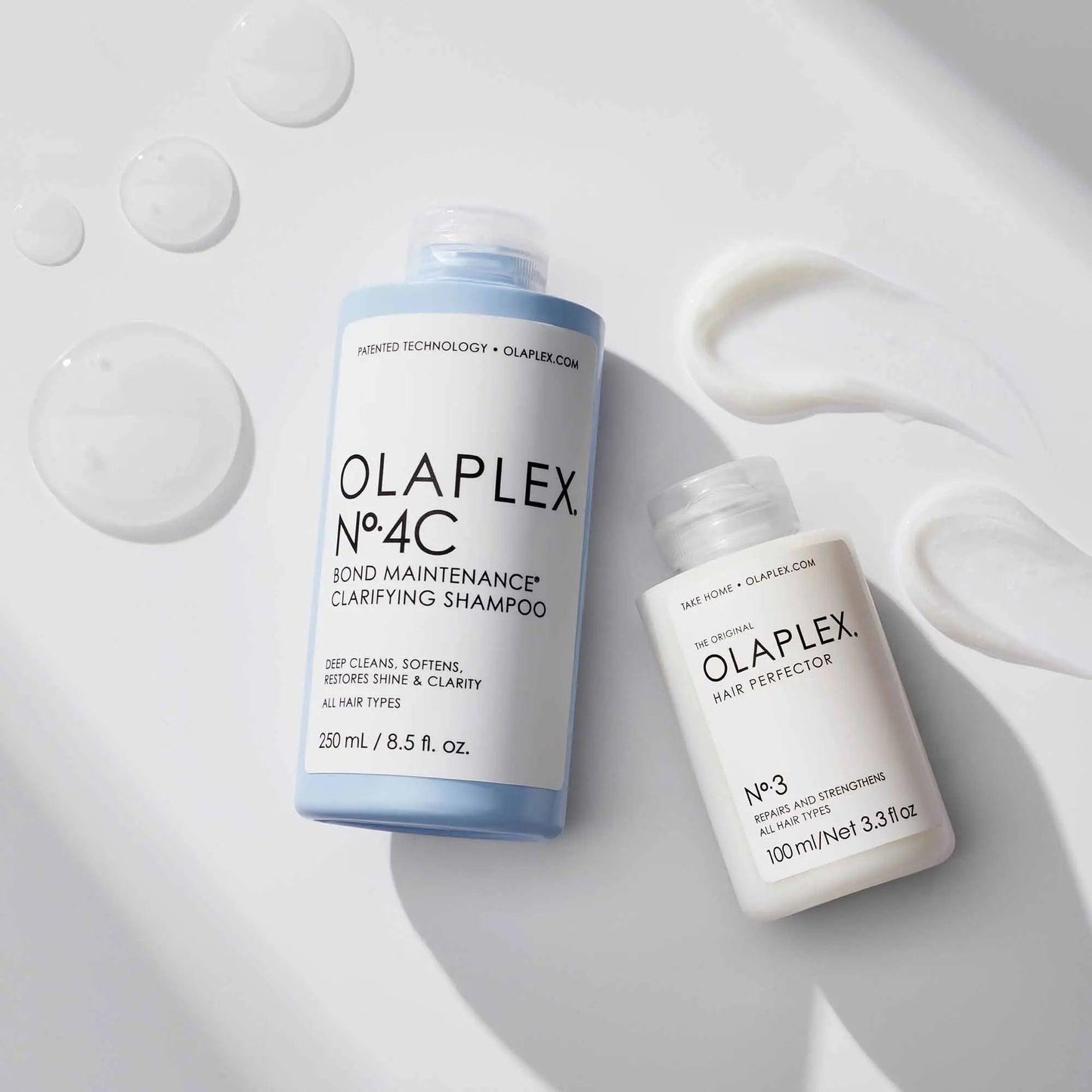Olaplex No. 4C Bond Maintenance Clarifying Shampoo and No. 3 Hair Perfector bottles with shampoo textures. Ideal for all hair types.