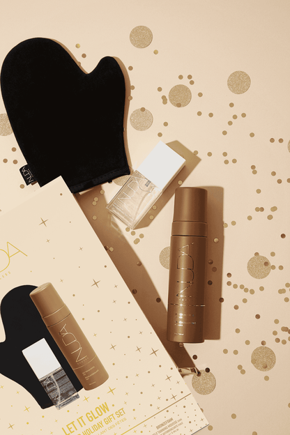 Nuda's Bronzed Holiday Gift Set with self tanning mousse, face tan water, and tanning mitt on a festive background.