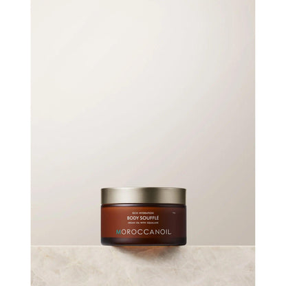 Original Body Soufflé by Moroccanoil in a jar on a marble surface, showcasing a lightweight whipped moisturizer for hydration.