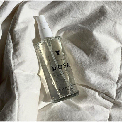 Rosa skincare product bottle on wrinkled white fabric in natural light.