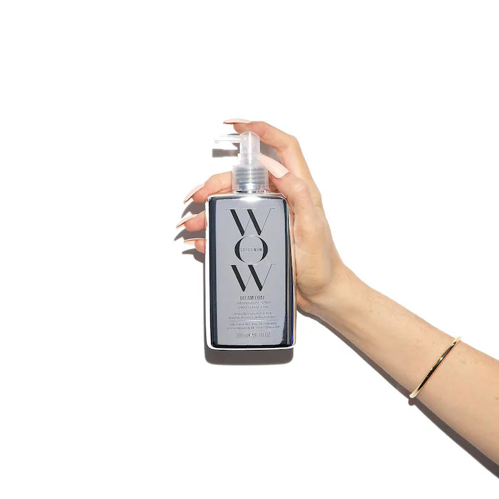 Dream Coat Supernatural Spray held in hand, showcasing its sleek bottle design and anti-frizz benefits.