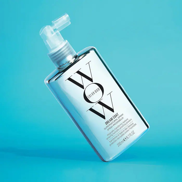 WOW Dream Coat Supernatural Spray bottle on a blue background, anti-frizz treatment for glossy hair.