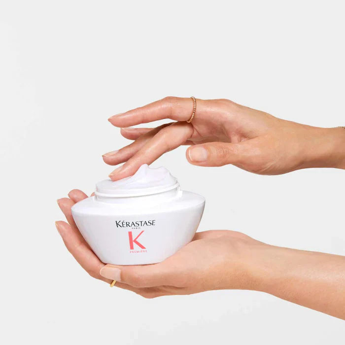 Woman's hands holding Kerastase Masque Filler Reparateur for damaged hair, showcasing the rich hair mask inside.