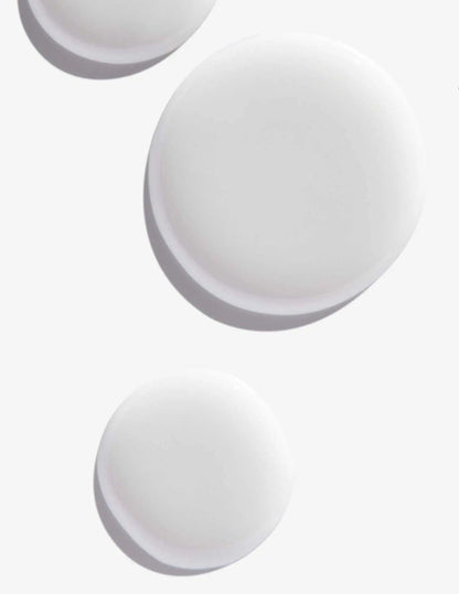 White round droplets of Scalp Relief Dandruff Shampoo on a light background, showcasing its smooth texture.