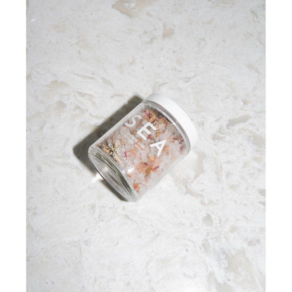 Glass jar of sea salt on marbled surface, labeled 'SEA'
