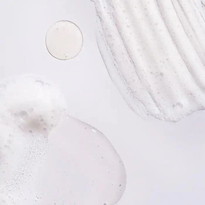 close-up of Oribe Serene Scalp Oil Control Shampoo texture, showcasing a foamy and creamy consistency on a light background