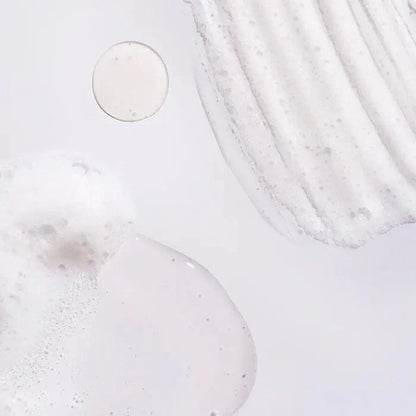 close-up of Oribe Serene Scalp Oil Control Shampoo texture, showcasing a foamy and creamy consistency on a light background