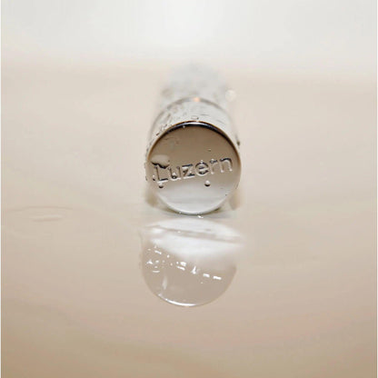 Close-up of Luzern serum bottle featuring a reflective surface, showcasing luxury skincare packaging.