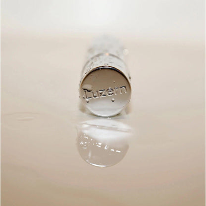 Lucerne skincare product bottle reflection on water surface.