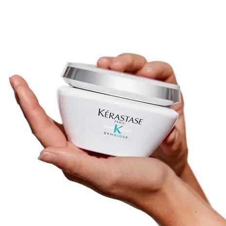 Kerastase Symbiose Masque Revitalisant Essentiel held in a hand, ideal for nourishing and revitalizing all hair types.