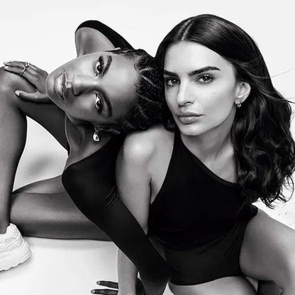 Two women posing in stylish black outfits, showcasing elegance and confidence in a striking black and white photo.