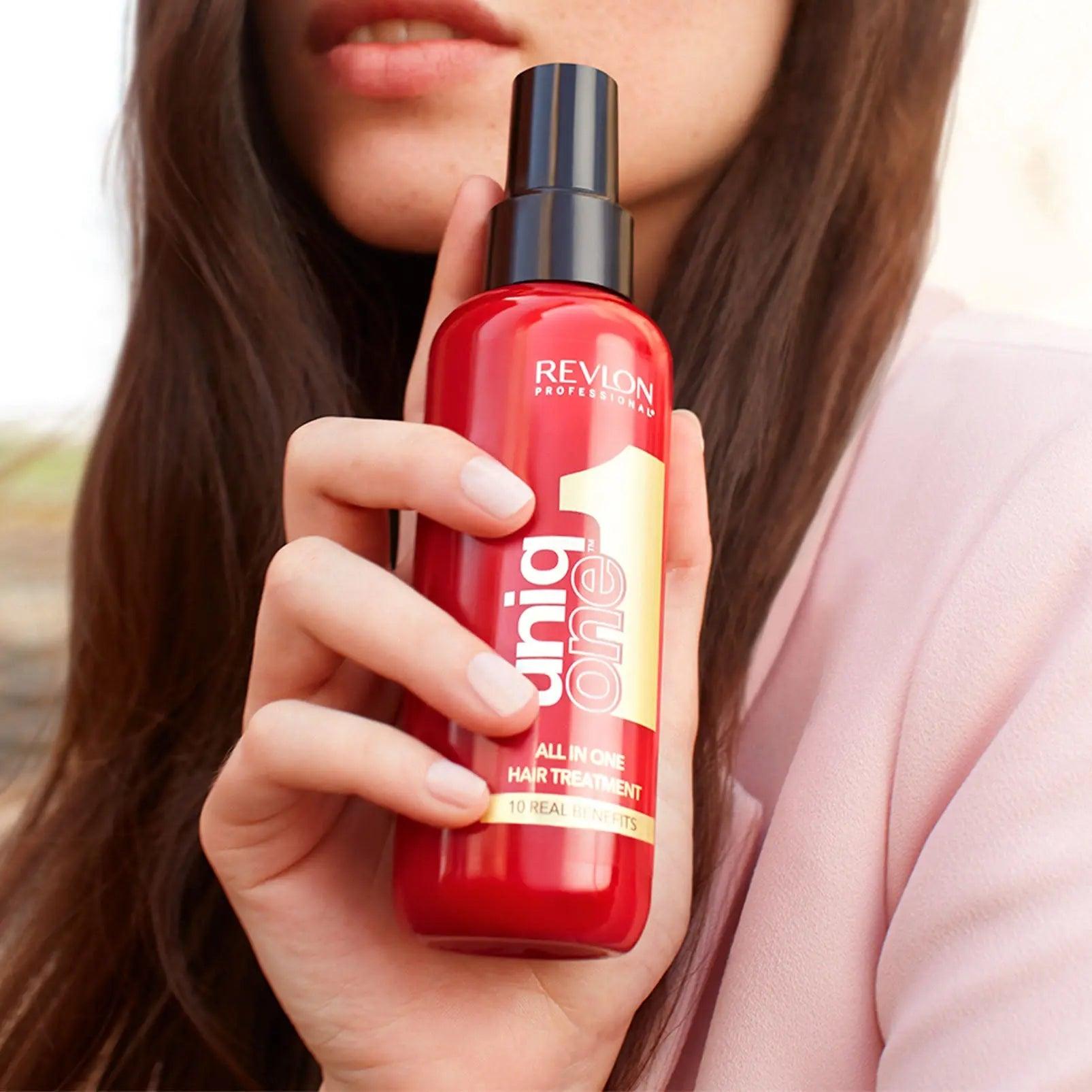 Woman holding Revlon Professional Uniq One All in One Hair Treatment spray bottle