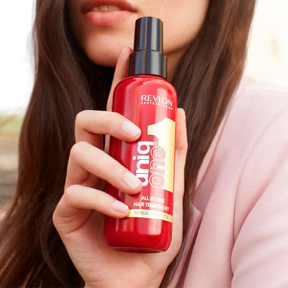 Woman holding Revlon Professional Uniq One All in One Hair Treatment spray bottle