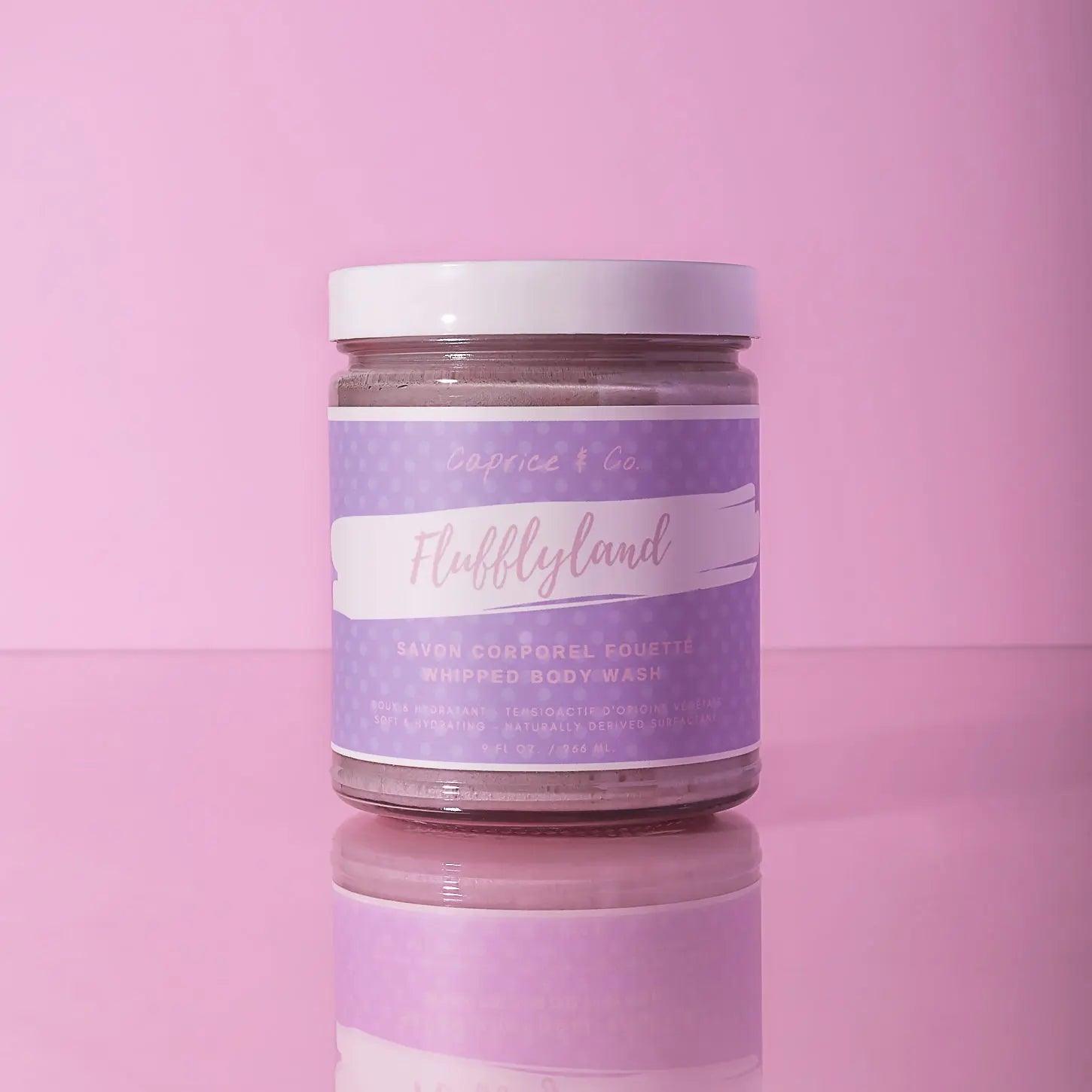 Fluffyland whipped body wash in a clear jar with lavender label on pink background, perfect for moisturizing skin.
