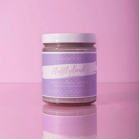 Fluffyland whipped body wash in a clear jar with lavender label on pink background, perfect for moisturizing skin.